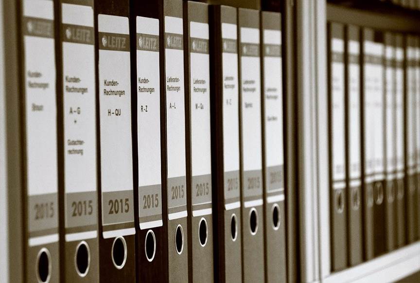 An image of folders containing business documents sitting on shelves. 