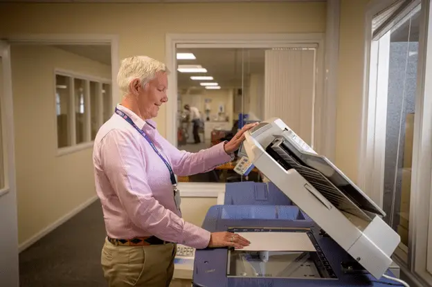 Older woman photocopying paper in an office