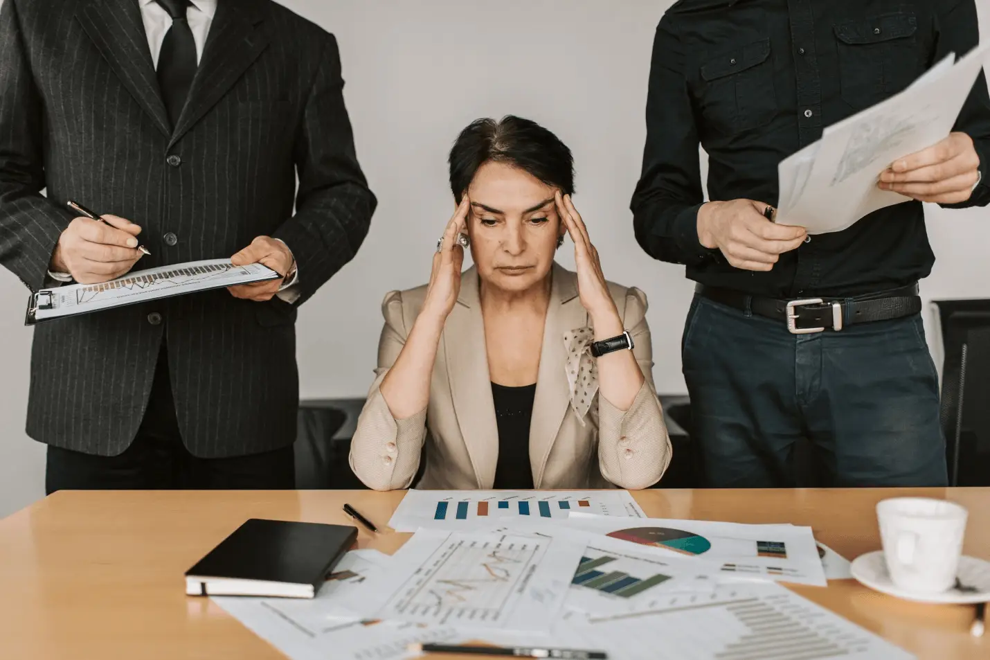 A woman sitting on office table and holding her head